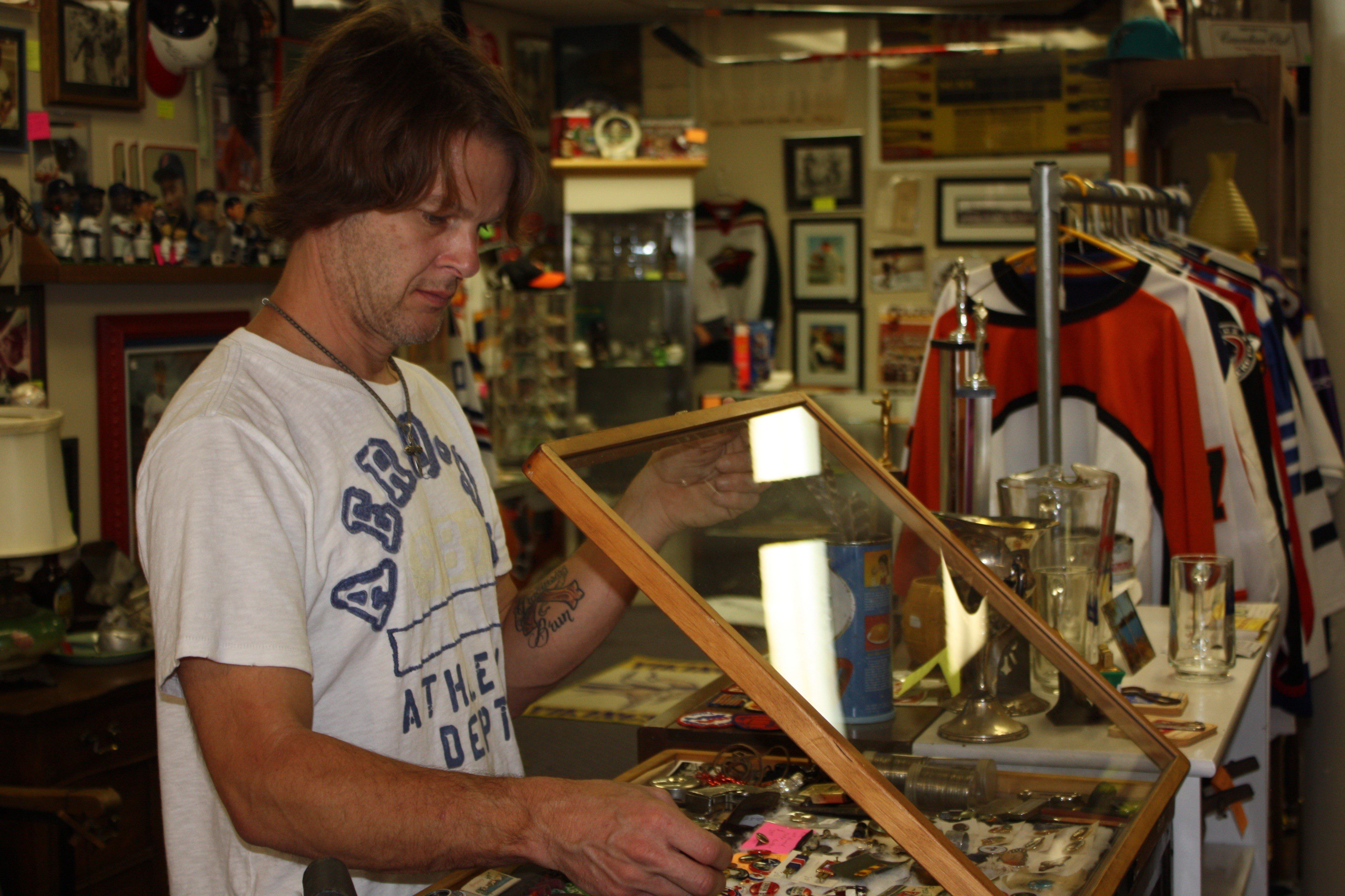 kyle in shop-3 man opening up a glass container of collectibles - Kyle's Kollectibles