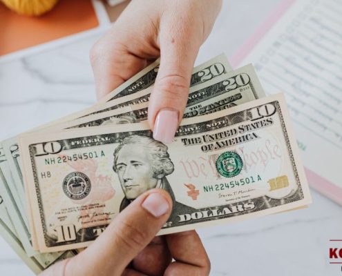 two hands exchanging American currency - Kyle's Kollectibles buying process